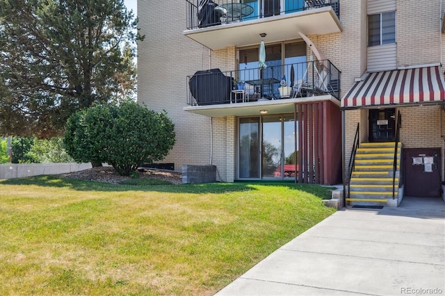 7801 W 35th Ave Unit 1, Wheat Ridge, CO 80033 - doorway to property with brick siding, a lawn, and a balcony
