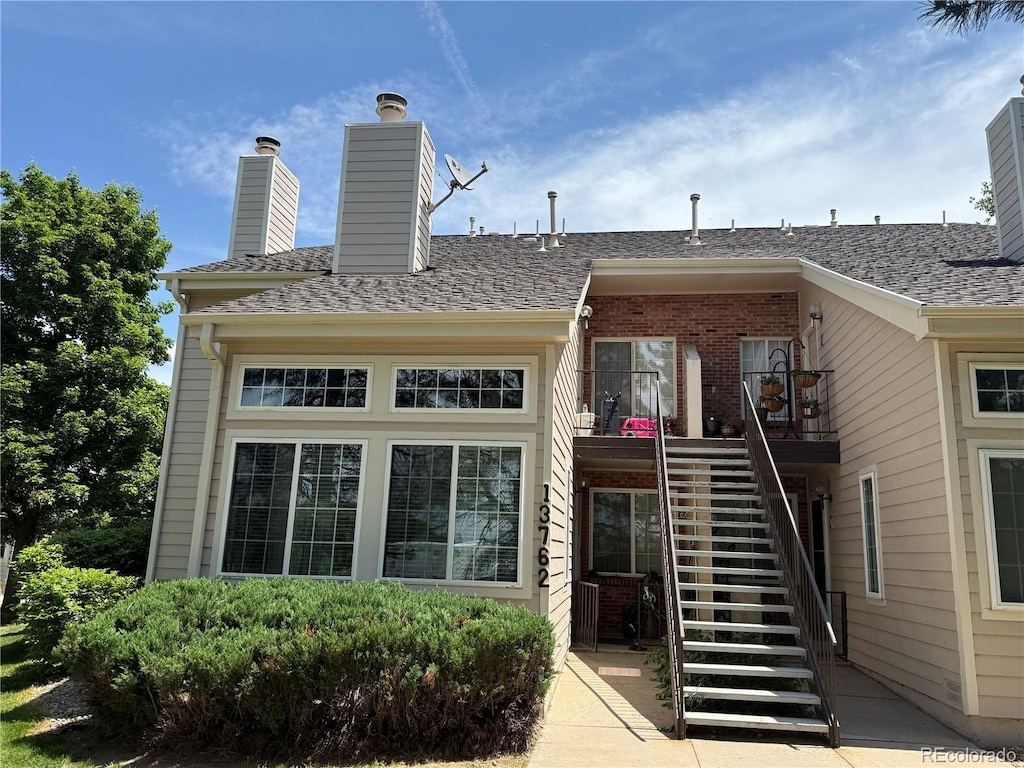13762 E Lehigh Ave Unit B, Aurora, CO 80014 - rear view of property with stairway, a chimney, and brick siding