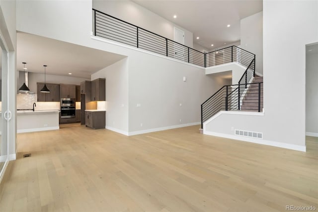 unfurnished living room with a high ceiling and light hardwood / wood-style flooring