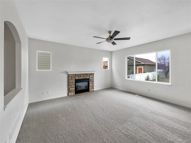 unfurnished living room with carpet floors, visible vents, a fireplace, baseboards, and ceiling fan