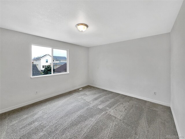 carpeted spare room with baseboards and visible vents