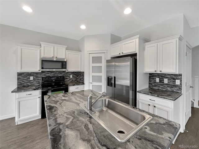 kitchen with white cabinetry, appliances with stainless steel finishes, a sink, and wood finished floors