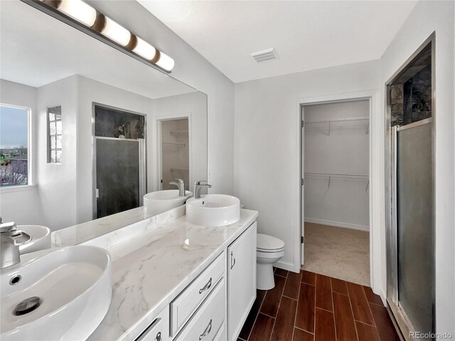 bathroom with a sink, a shower stall, double vanity, and visible vents