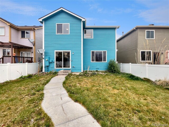rear view of house with fence and a yard
