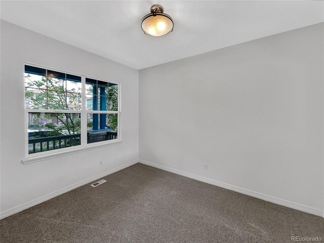 empty room with baseboards, visible vents, and dark carpet