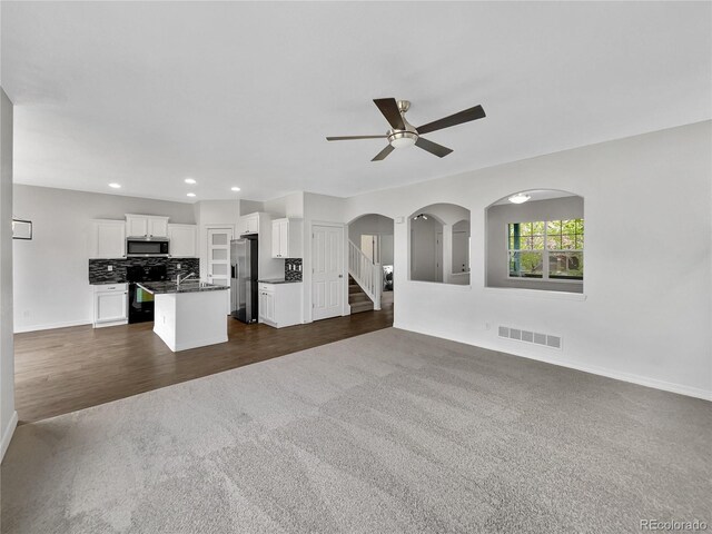 unfurnished living room with a ceiling fan, visible vents, baseboards, dark colored carpet, and recessed lighting