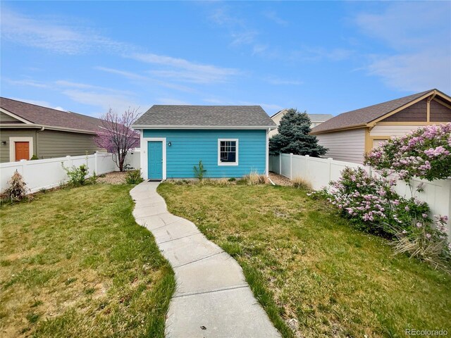 view of front of house with a shingled roof, a fenced backyard, and a front lawn