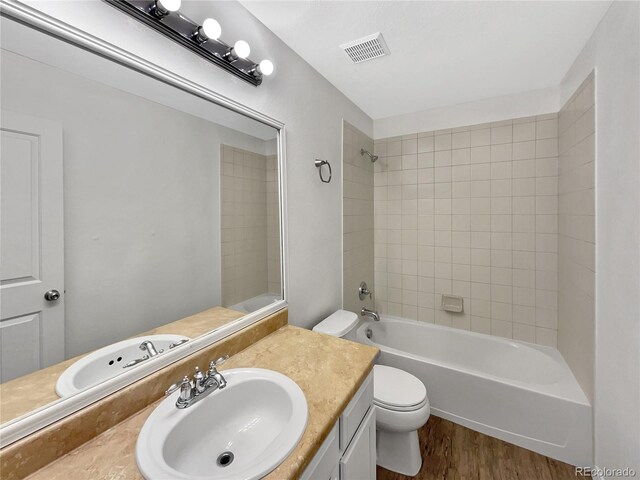 bathroom featuring visible vents, wood finished floors, vanity, toilet, and bathing tub / shower combination