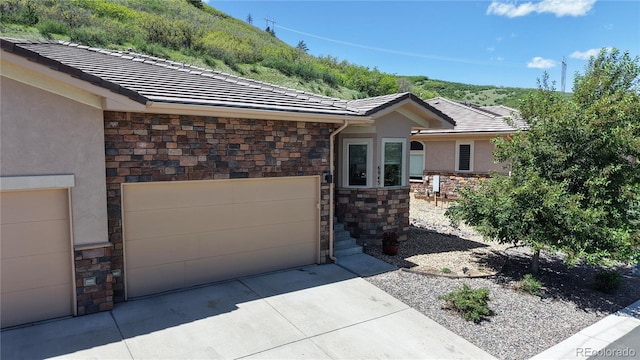 6945 Fargo Trl, Littleton, CO 80125 - view of front of house featuring stone siding, concrete driveway, and stucco siding