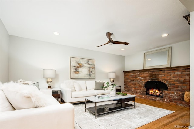 living room with light wood-type flooring, ceiling fan, a fireplace, and recessed lighting