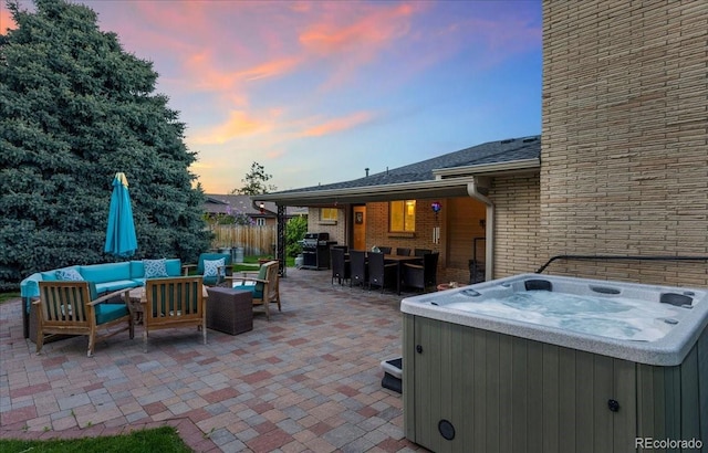 patio terrace at dusk featuring a hot tub, a grill, fence, and an outdoor hangout area