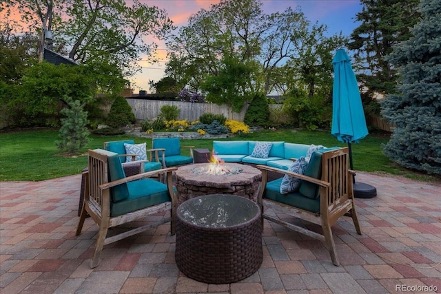 patio terrace at dusk with an outdoor living space with a fire pit, a fenced backyard, and a yard