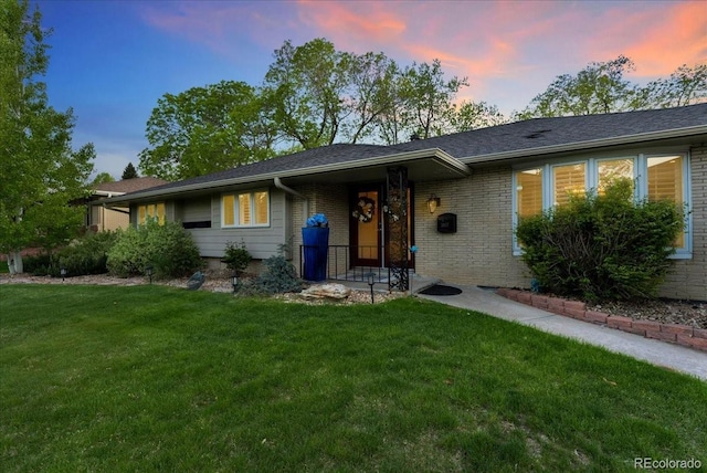 ranch-style house featuring brick siding and a yard