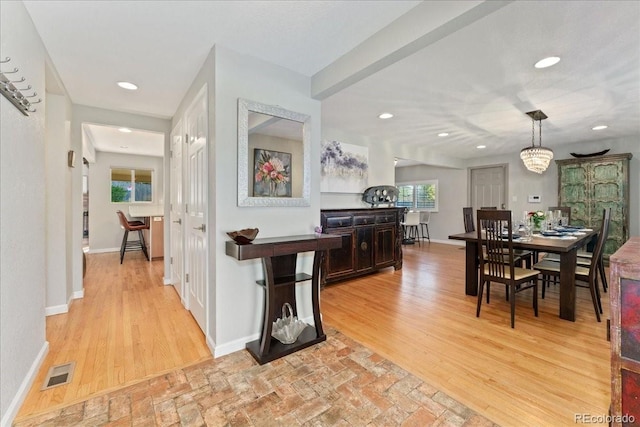 hallway featuring light wood finished floors, baseboards, visible vents, and recessed lighting