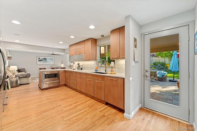 kitchen with light countertops, a sink, a wealth of natural light, and light wood-style floors