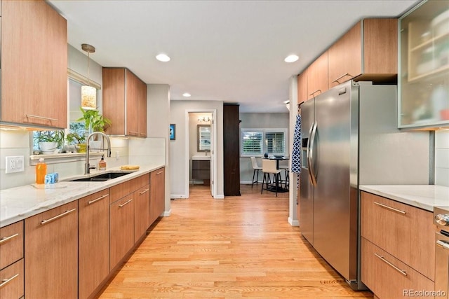 kitchen with light wood-style floors, recessed lighting, a sink, and light stone counters