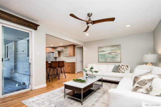 living area with light wood-type flooring, baseboards, a ceiling fan, and recessed lighting