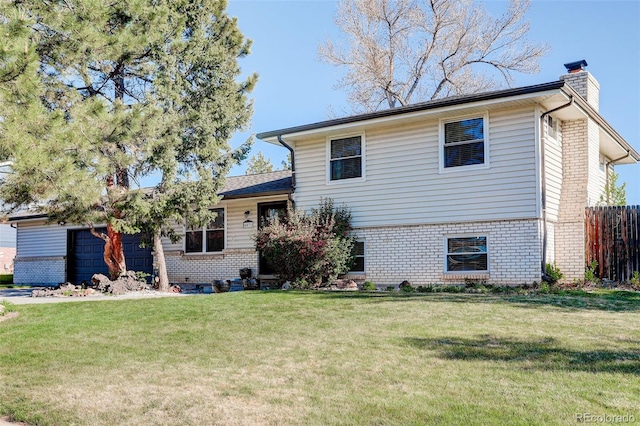 split level home with a chimney, an attached garage, a front lawn, and brick siding