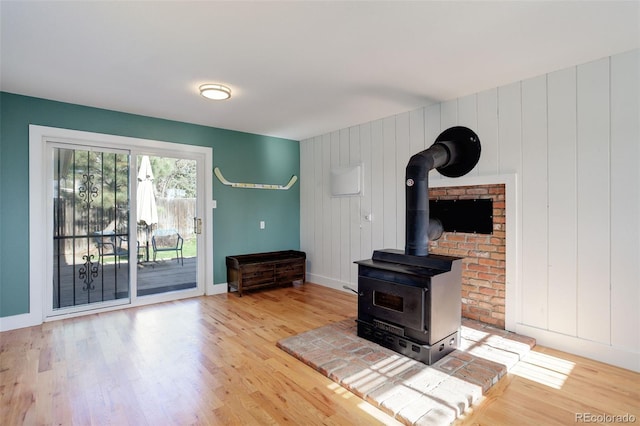 unfurnished living room with baseboards, a wood stove, and wood finished floors