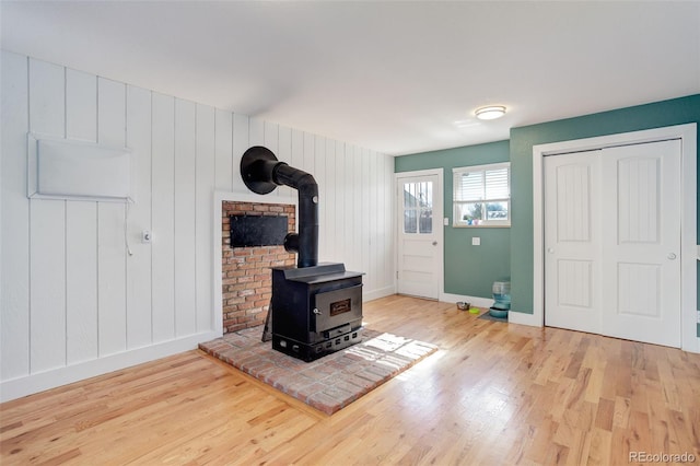 unfurnished living room featuring baseboards, a wood stove, and wood finished floors