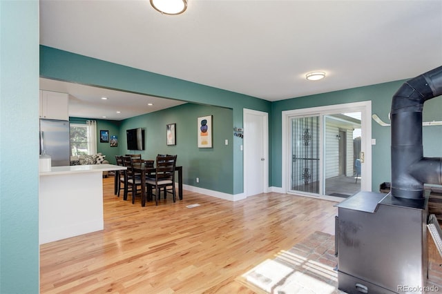 living area with a wood stove, baseboards, and light wood finished floors
