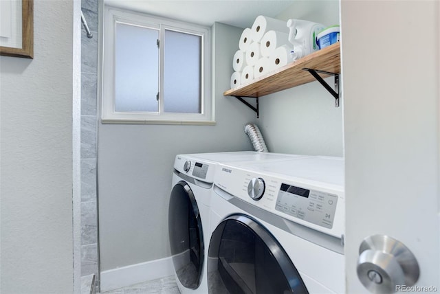 washroom with laundry area, baseboards, and washing machine and dryer