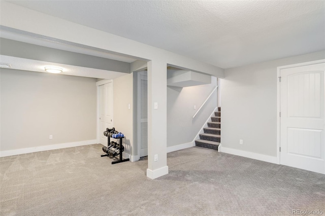 finished basement with baseboards, carpet flooring, stairs, and a textured ceiling