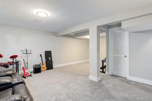 finished below grade area featuring carpet flooring, a textured ceiling, visible vents, and baseboards