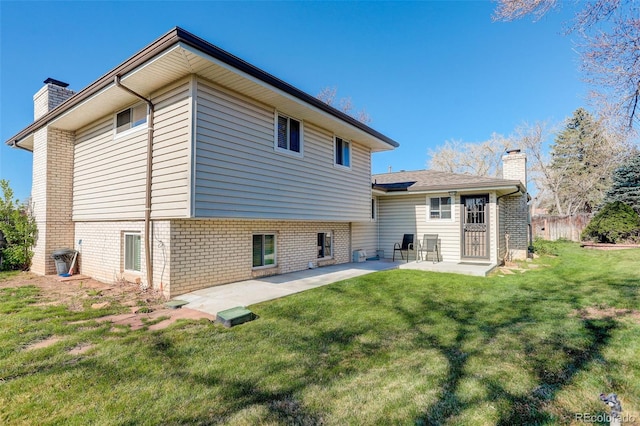 back of property with brick siding, a chimney, and a patio