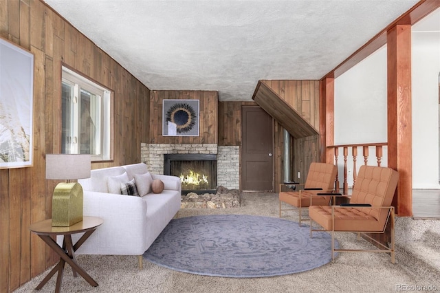 living room with a textured ceiling, wood walls, and a fireplace