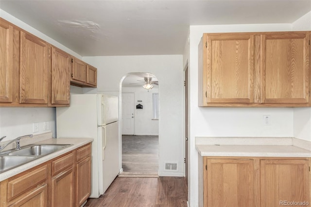 kitchen with dark wood-style floors, arched walkways, light countertops, a ceiling fan, and a sink