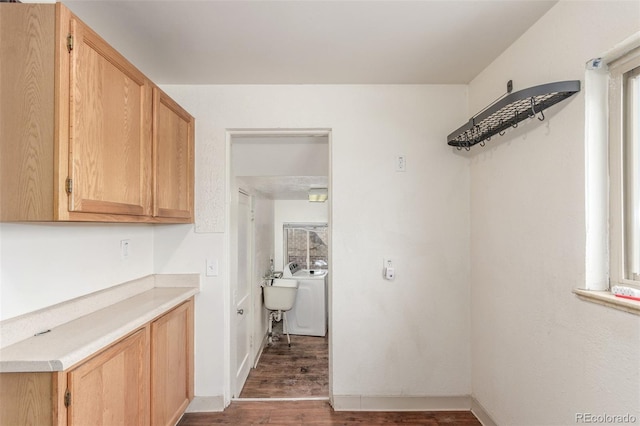 clothes washing area featuring dark wood finished floors, washer / clothes dryer, a sink, laundry area, and baseboards