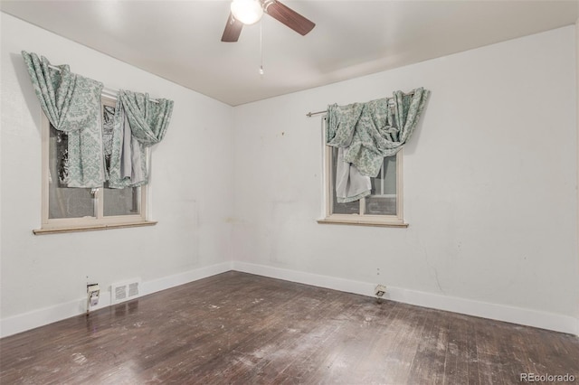 empty room featuring a ceiling fan, dark wood-style flooring, visible vents, and baseboards