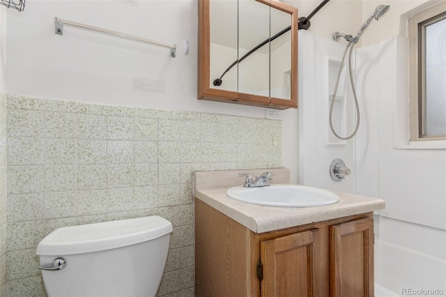 bathroom featuring bathtub / shower combination, toilet, vanity, tile walls, and wainscoting