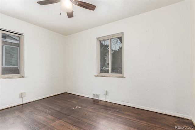 unfurnished room featuring dark wood-style floors, ceiling fan, visible vents, and baseboards