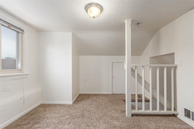 bonus room featuring visible vents, light carpet, vaulted ceiling, a textured ceiling, and baseboards