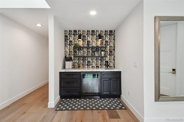 bar with beverage cooler and light hardwood / wood-style floors