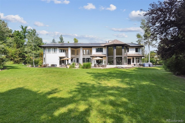 rear view of house featuring a lawn and a patio