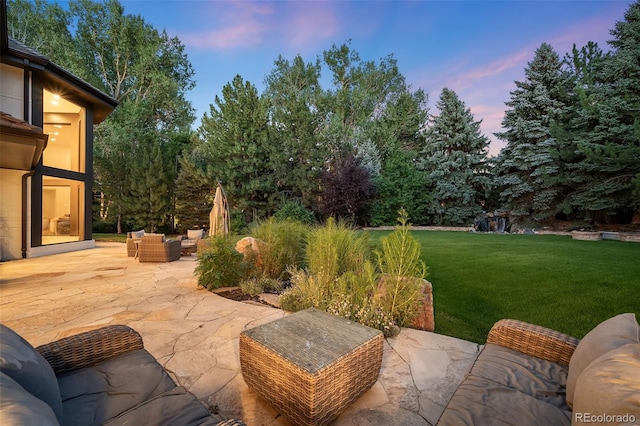 patio terrace at dusk featuring an outdoor living space and a yard