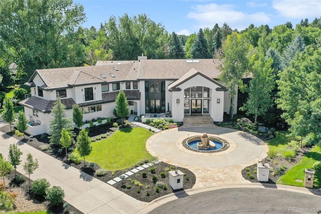 view of front facade featuring a front yard, driveway, a chimney, and stucco siding