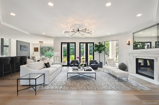 living room with a high end fireplace, a chandelier, and light hardwood / wood-style flooring