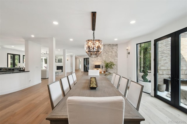 dining room with a wealth of natural light, an inviting chandelier, and light wood-type flooring