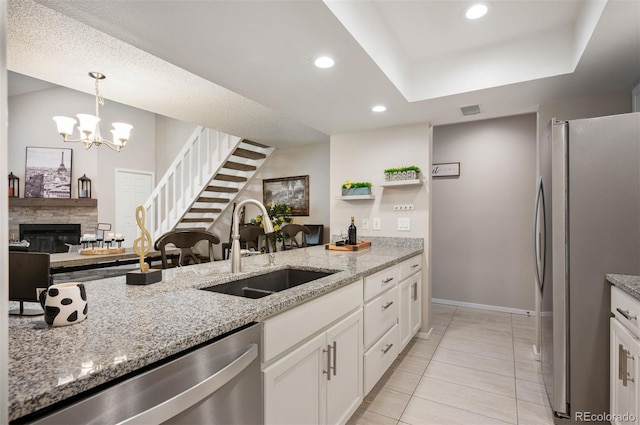 23585 Genesee Village Rd Unit E, Golden, CO 80401 - kitchen with stainless steel appliances, light tile patterned floors, white cabinets, light stone countertops, and decorative light fixtures