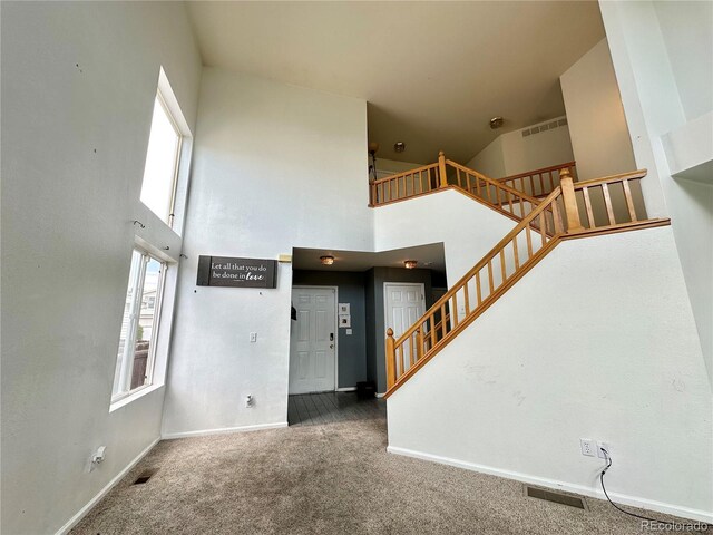 2033 Espana Way, Aurora, CO 80011 - unfurnished living room featuring stairs, carpet floors, a high ceiling, and baseboards