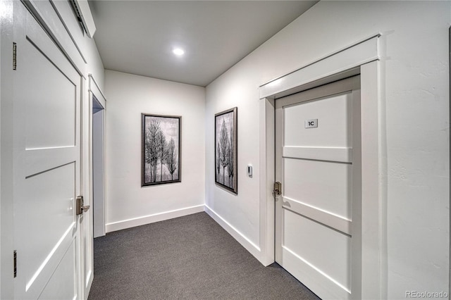 corridor featuring dark colored carpet and baseboards