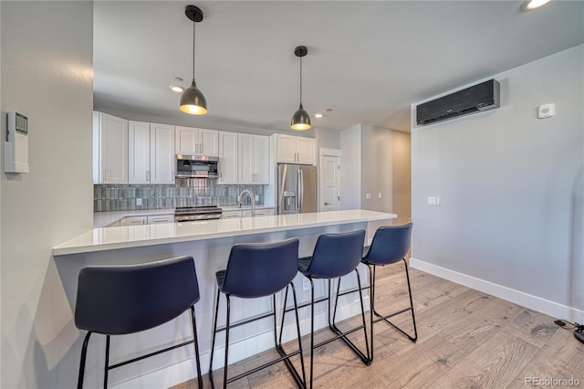 kitchen with tasteful backsplash, appliances with stainless steel finishes, a kitchen breakfast bar, light countertops, and a wall mounted AC