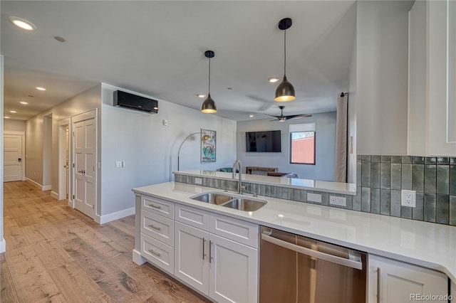 kitchen featuring an AC wall unit, white cabinets, a sink, and stainless steel dishwasher