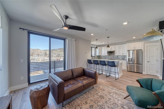 living room with light wood-style floors, ceiling fan, baseboards, and recessed lighting