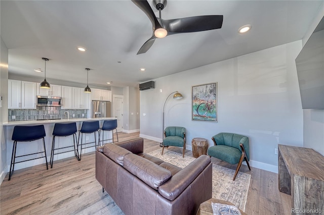 living room featuring light wood-style floors, recessed lighting, ceiling fan, and baseboards