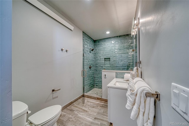 full bath featuring toilet, a shower stall, vanity, wood finished floors, and baseboards